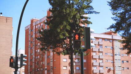 Pedestrian traffic light in red in a city with buildings behind
