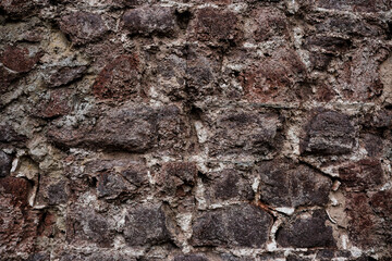 A wall made of stone with a rough texture. The wall is brown and white