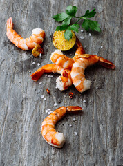 Grilled Shrimp Garnished With Lime And Herbs On Rustic Wooden Plate. prawns are arranged on a weathered wooden surface, accompanied by lime slices and herbs, showcasing a delightful seafood dish.