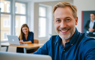 Adult man in casual clothes while working in office at computer monitor. Friendly adult man at workplace.