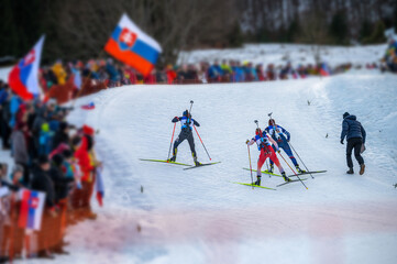 Biathlon race, female athletes climbs a hill. Winter sport, nordic ski race