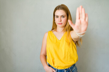 Serious young woman signals to stop, expressing refusal and protest