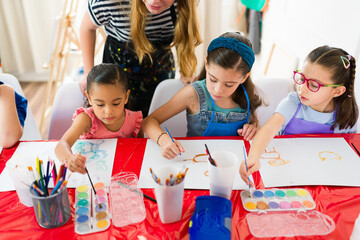 Group of elementary school students painting with watercolors and having fun during a creative art...