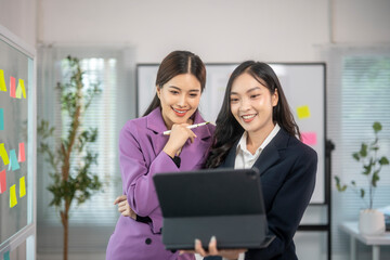 Two women in business attire are looking at a computer screen