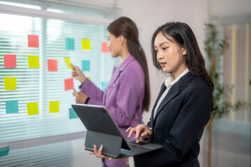Two women in business suits are working on a project together
