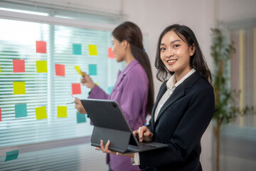 Two women in business attire are working on a project together