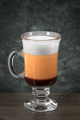 Irish Coffee glass on the wooden table against the wall in grunge style. Bar theme. Dark environment. 3d rendering.