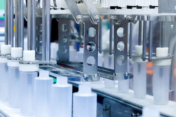 robot arm moving plastic bottle to conveyor belt of auto capping and labeling machine at cosmetic and skin care manufacturing. cosmetic industry and ai technology machinery concept.