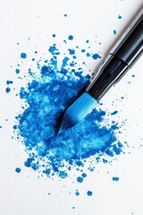 Blue paint splattered on white paper with brush.