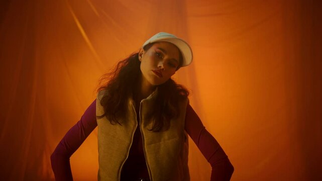 Stylish model posing elegantly in a trendy outfit against a bright orange background