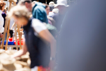 Cross section of unidentifiable blurred out people in a crowd shopping at a market stall 