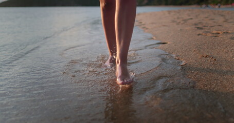 Woman barefoot legs close up walking sand beach along sea shore. Water waves splashing, sunset soft light. Outdoor lifestyle travel on summer holiday vacation. Concept relax freedom. POV
