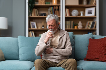 Senior man, widower or divorced, feeling sad, worry, abandoned and depressed, sitting alone at home, crying. Loneliness and sadness of older male with white hair and beard.