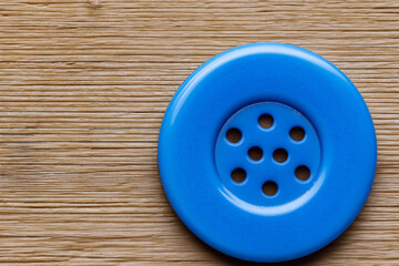 Button on wooden in blue. design equipment object concept. a button lies on a wooden in bright blue. a button lies on a wooden in bright lifestyle blue.