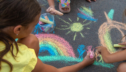 Children draw with chalk on the asphalt. Selective focus.