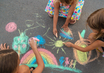 Children draw with chalk on the asphalt. Selective focus.