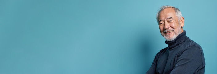 Cheerful senior man smiling confidently against turquoise background with copy space