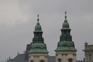Obraz premium Twin domes of a historical church rise against a cloudy sky in a European city, showcasing architectural elegance on a dreary day