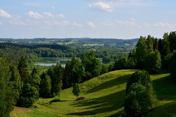 A view from the top of a tall hill or mountain showing various fields, meadows, and pasturelands surrounded with forests, moors, small villages and farmlands spotted on a sunny summer day in Poland