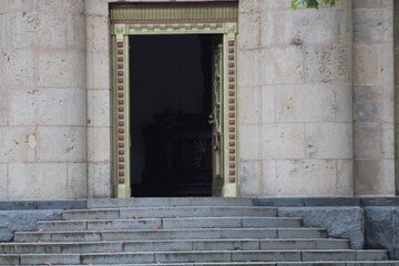 An ornate doorway leading into a shadowy interior at a historic stone building, flanked by steps...