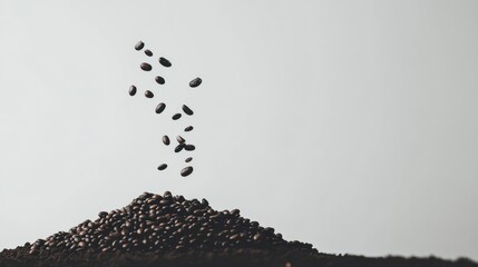 Coffee beans falling onto a mound of ground coffee against a minimalist background.