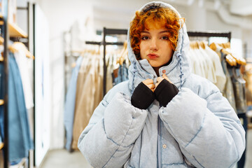 young attractive red-haired woman trying on a warm jacket