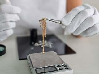 Jeweler weighs gold chain in pawn shop on scales