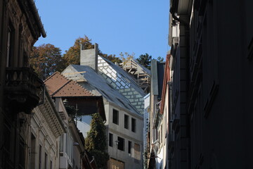 Modern architecture emerges among historic buildings under a clear sky in an urban setting during late afternoon