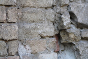 Crumbling brick wall revealing layers of weathered masonry and plaster in an abandoned structure