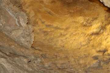 Unique textured ceiling of a cave showcasing natural patterns and warm colors in a dimly lit environment
