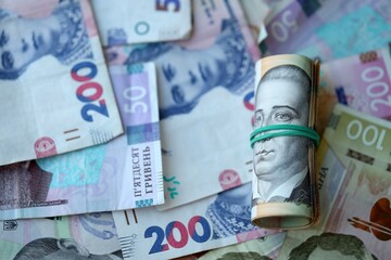 Roll of 500 Ukrainian Hryvnia money bills lies on big pile of ukrainian currency money close up