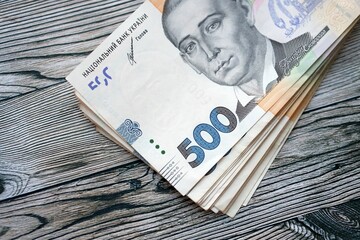 Many five hundred hryvnia money bills lies on wooden background. Ukrainian national currency close...