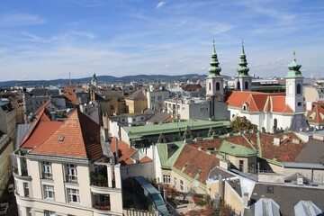 Obraz premium A vibrant view of rooftops and towers in a historic European city with bright blue skies on a sunny day