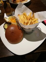 Delicious burger with a sunny-side-up egg and crispy fries served at a cozy restaurant during dinner time