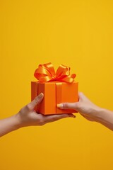 Vibrant orange gift box with a shiny ribbon exchanged between hands against a bright yellow background