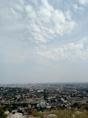 Panoramic view of a vibrant cityscape under a cloudy sky from a hillside location in the afternoon