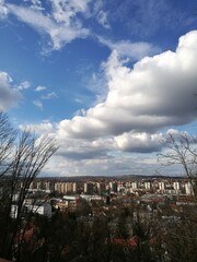 City view under a vast blue sky with fluffy clouds and distant hills in a tranquil afternoon setting
