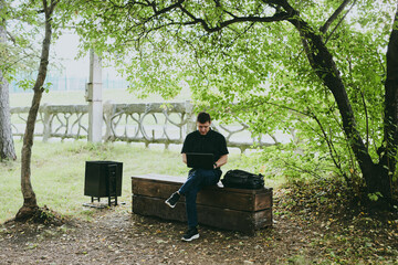 Fototapeta premium Portrait of young freelance programmer man working with laptop in forest park, software developer, IT technologies
