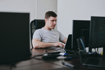 Portrait of young Caucasian male programmer working with laptop in office, software developer, IT technology