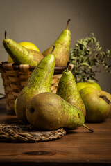 View of pears and basket on wooden table, dark background, vertical with copy space