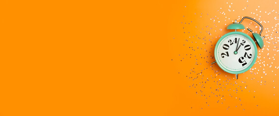 New Year 2025 background concept. 2024 changes to 2025 on an alarm clock on a colored background with festive glitter on New Year's Eve and Christmas.