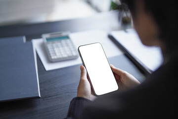 Businessman sits on chair and using smartphone at office/workplace