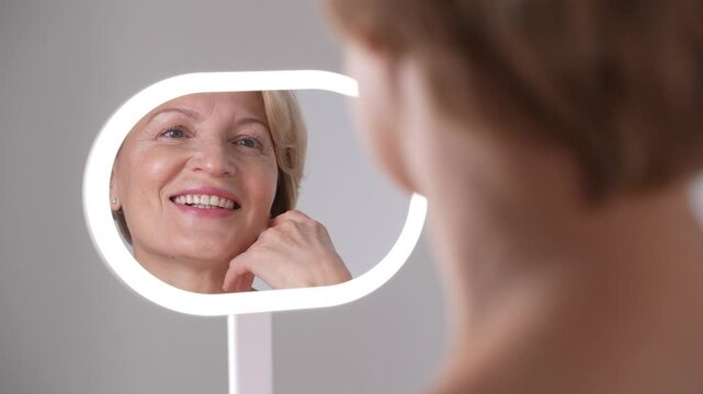 A confident and empowered woman in her 50s joyfully explores, cherishes, and appreciates her skin with a sense of elegance and grace