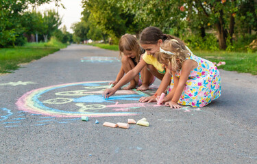Children draw with chalk on the asphalt. Selective focus.