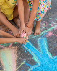 Children draw with chalk on the asphalt. Selective focus.