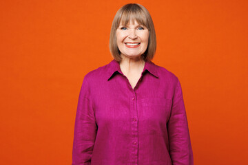 Elderly smiling happy satisfied cheerful fun blonde woman 50s years old she wearing purple shirt...