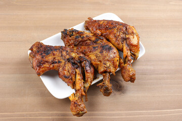 Grilled chicken legs on a white plate, top view food table