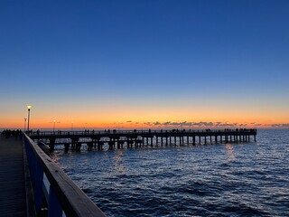 Fototapeta premium Palanga pier bridge with people resting against the background of the sea sunset