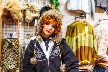 portrait of attractive red-haired curly girl, in winter fur hat, stylish faux fur hat