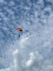 Skydiver with a blue little canopy of a parachute on the background a blue sky and white clouds, close-up. Skydiver under parachute above the stormy clouds. Lithuania